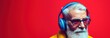 Portrait of senior man with headphones listening to music on red background. Music Streaming Service Concept with Copy Space.