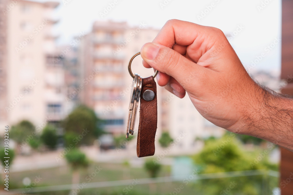 Man showing keys to a new house in front of blurred condos, the image ...