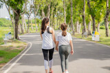 Fototapeta Las - Older sister and younger sister walking in the park Feel comfortable on holidays and relax and exercise.