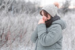 © fantom_rd - young woman in hat warms her hands with breath, cute girl walking on in frosty day, winter walk