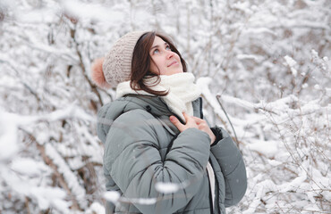 young woman looking up on winter nature, pretty beautiful girl among trees covered with snow walking in white forest and enjoying