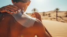 Close-up Of Sunscreen Being Applied On A Man's Back, Extreme Summer Setting In A Desert, Cacti And Sand Dunes In The Background