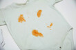 Orange stains on children's clothes from fruit puree. The concept of cleaning stains on clothes with an oxygen stain remover, close-up