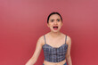 A young Asian woman nagging and complaining, yelling with an annoying voice. Isolated on a red background.