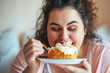 Plus size woman is eagerly eating a cake