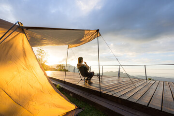 Wall Mural - Woman go camping and sit outside with the snack under sunset