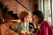© Marko Geber - Two diverse young women talking during home party