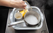 A woman's hand pours hot water into a basin with dirty dishes and environmentally friendly oxygen bleach. Washing dishes from grease and dirt.