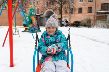 Wall Mural - Child girl playing in snow playground in winter, 5-6 years old kid