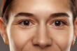 Close-up of female's brown eyes, no makeup looking on camera. Health care, vision. Woman smiling. Concept of natural beauty, cosmetology and cosmetics, skin care