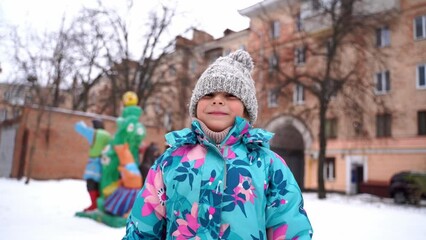 Wall Mural - Child girl playing in snow playground in winter, 5-6 years old kid