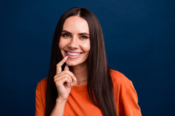 Wall Mural - Photo of nice woman with straight hairdo dressed orange t-shirt finger on teeth advertise dental clinic isolated on dark blue background