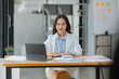 © SOMKID - Asian Businesswoman working with tablet computer at office desk, Business accounting analysis report and financial concept.