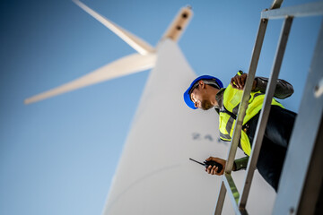 Asian engineers working in fieldwork outdoor. Workers check and inspect construction and machine around building project site. Wind turbine for electrical of clean energy and environment sustainable.