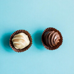 Fresh and old spoiled dark chocolate candies on light blue table background. Pastel color. Compare two pralines. Top down view.