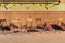 Tables And Chairs On The Sidewalk Near The Cafe Building On A Sunny Day