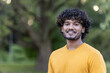 © Tetiana - Close-up portrait of a young Indian male athlete standing in the park and smiling at the camera