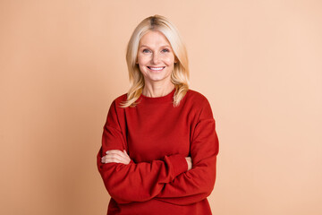 Wall Mural - Photo of confident cheerful woman wear red sweater arms crossed smiling isolated beige color background