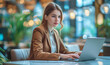 © evgeniia_1010 - Portrait of a young blonde woman in a brown suit working on a laptop in a modern and bright coworking space. Productive work outside the office, online business using the Internet