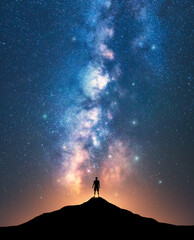 Wall Mural - Milky Way and sporty man on mountain peak at starry night
