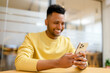 © Vadim Pastuh - Selective focus at trendy smartphone in hands of happy smiling Indian man, male student chatting online, using phone for texting, scroling news