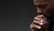 © herlanzer - black man praying to god Caribbean man praying with black background with people stock photo