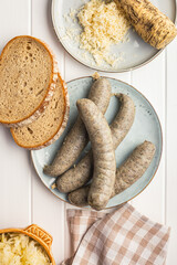 Wall Mural - White pudding sausage. Pork product on plate on white table. Top view.