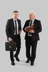 Poster - Mature brothers in suits with notebook on grey background