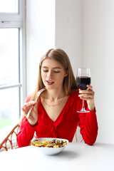 Wall Mural - Young woman with glass of wine eating tasty pasta in restaurant