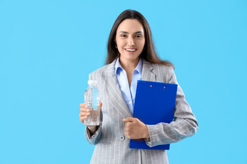 Wall Mural - Young businesswoman with clipboard and bottle of water on color background