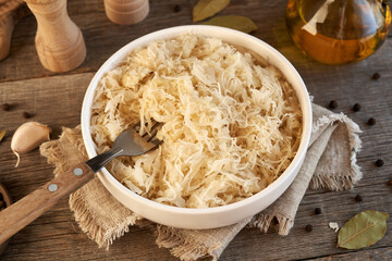 Wall Mural - Homemade fermented cabbage or sauerkraut in a bowl on a wooden table