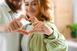 © Pixel-Shot - Happy couple in love making heart gesture at home, closeup