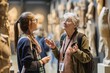 Mature woman looking at sculpture in art museum and talking with colleague. AI generated