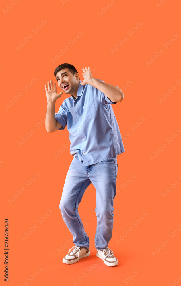 Afraid young man on orange background