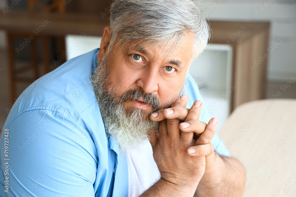 Afraid mature man at table in kitchen