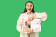 © Pixel-Shot - Young woman pointing at open magazine on green background