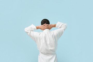 Sticker - Handsome young man in bathrobe on blue background, back view