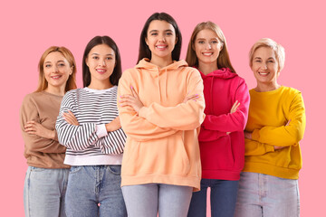 Wall Mural - Portrait of beautiful women with crossed arms on pink background