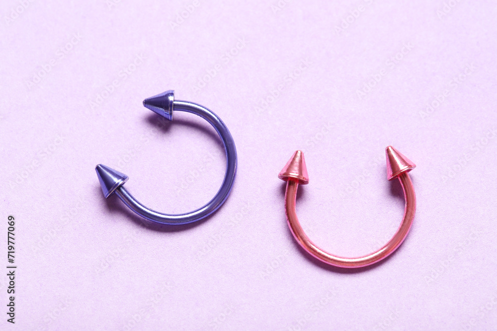 Colorful circular barbells for piercing on lilac background