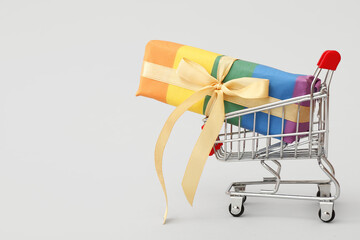 Small shopping cart with rainbow LGBT gift box on white background. Valentine's Day celebration