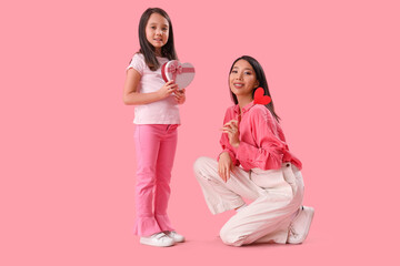 Wall Mural - Little Asian girl greeting her mother with Valentine's day on pink background