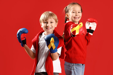 Sticker - Cute little children in boxing gloves with yellow ribbons on red background. Childhood cancer awareness concept