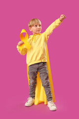 Sticker - Cute little boy in superhero costume with yellow ribbon on purple background. Childhood cancer awareness concept