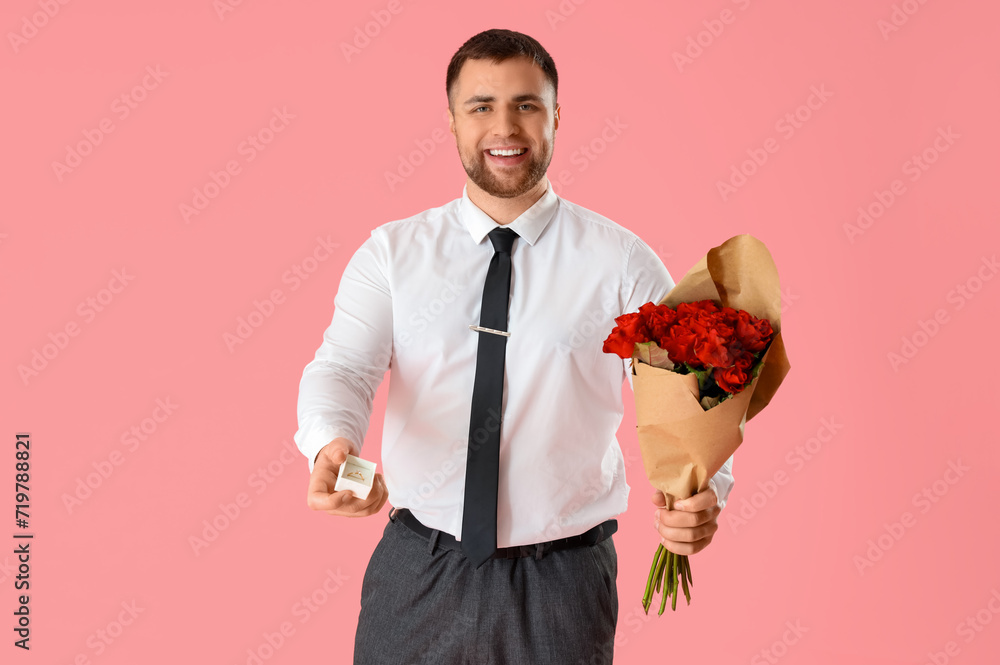 Handsome man with flowers and ring on pink background
