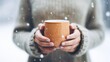 A Young woman's hand in a sweater holds a steaming warm tea mug outdoors in snowy winter. Coffee, tea, coffee mug, warm,