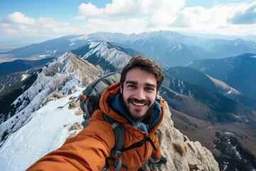 Hiker man reaches the summit of a mountain, capturing the triumphant moment by taking a selfie portrait. Convey the joy and accomplishment in his expression as he smiles at the camera