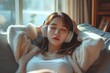 © sirisakboakaew - Beautiful young asian woman with headphones relaxing and listening to music on the sofa .
