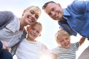 Poster - Below, parents and children in happy portrait outdoor in summer with love, freedom and embrace on blue sky. Family, hug and kids smile with support in backyard at home with mother and father