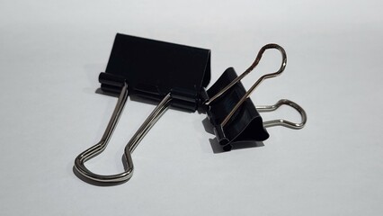 two black binder clips on a white surface