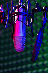 Professional studio microphone against acoustic foam panel background in neon light